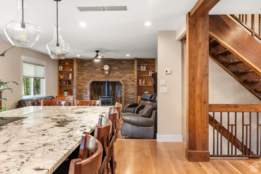 Kitchen featuring ceiling fan, recessed lighting, light wood-type flooring, light stone counters, and a kitchen breakfast bar
