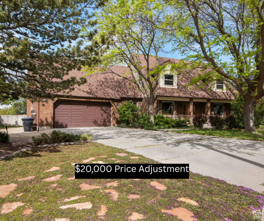 View of front of property with covered porch, concrete driveway, a garage, brick siding, and a shingled roof
