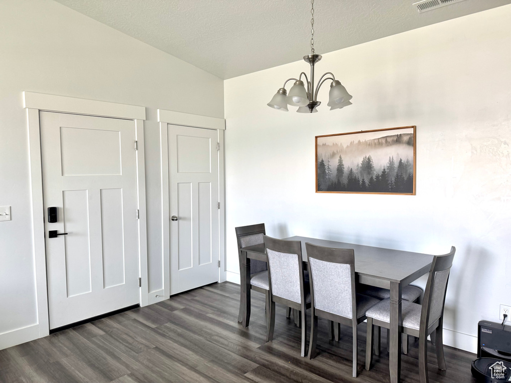 Dining space featuring dark wood-type flooring, baseboards, and a notable chandelier
