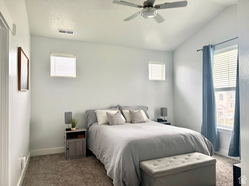 Carpeted bedroom with a textured ceiling, visible vents, baseboards, and a ceiling fan