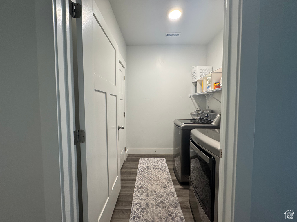Clothes washing area featuring independent washer and dryer, laundry area, visible vents, dark wood finished floors, and baseboards