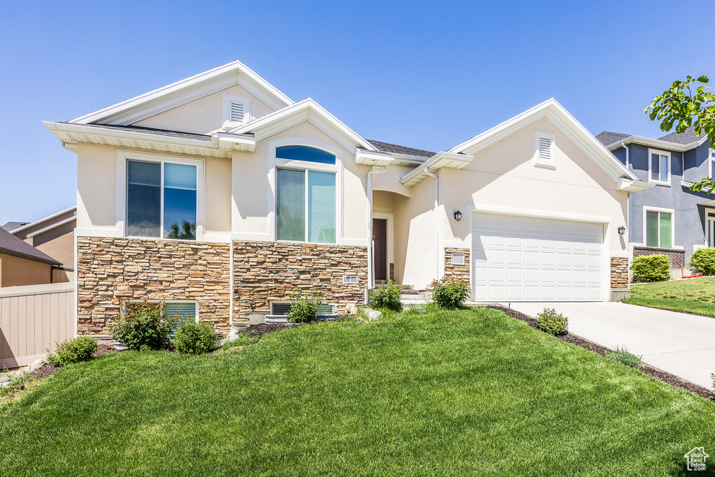 View of front of house with stone siding, stucco siding, driveway, and a front yard