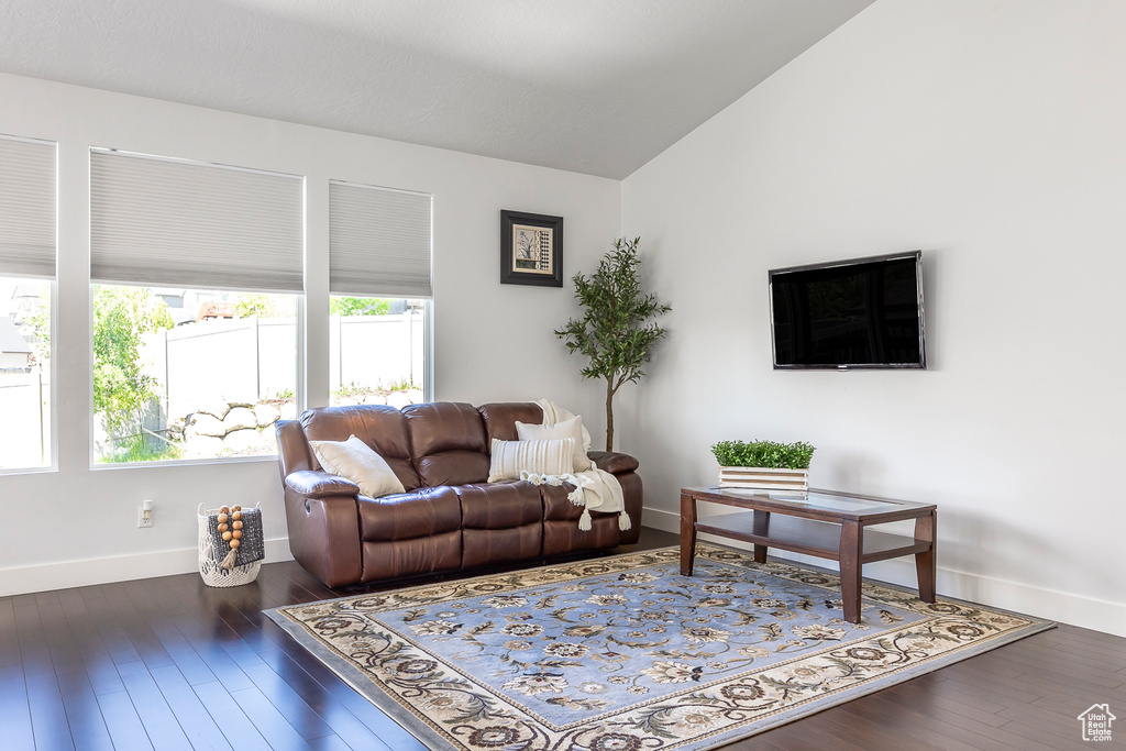 Living room with baseboards, vaulted ceiling, and wood finished floors
