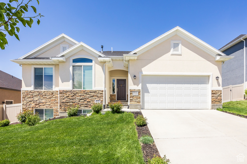 View of front of home featuring stone siding, stucco siding, driveway, and a garage