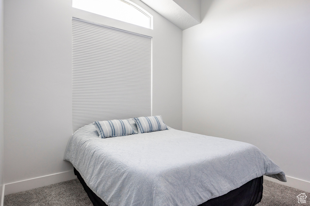 Carpeted bedroom featuring baseboards and vaulted ceiling