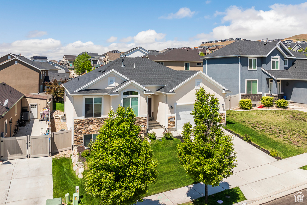 View of front of home featuring a gate, a residential view, stone siding, stucco siding, and driveway