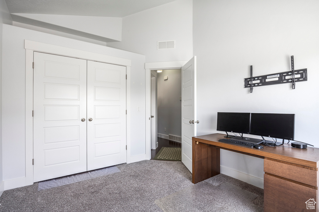 Carpeted office space with lofted ceiling and baseboards