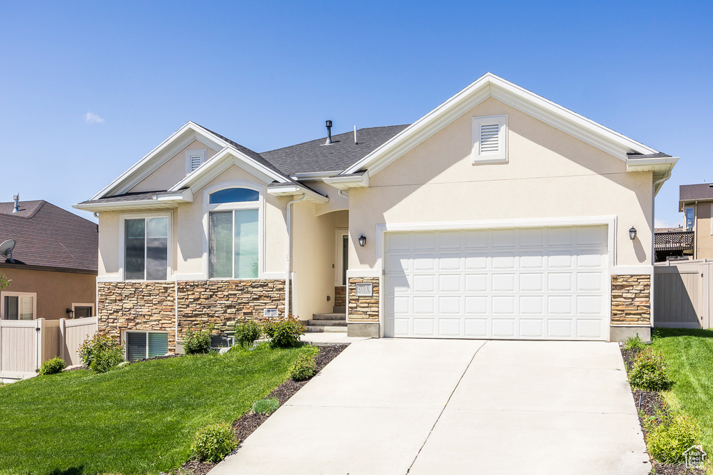 View of front of property featuring stone siding, stucco siding, an attached garage, and concrete driveway