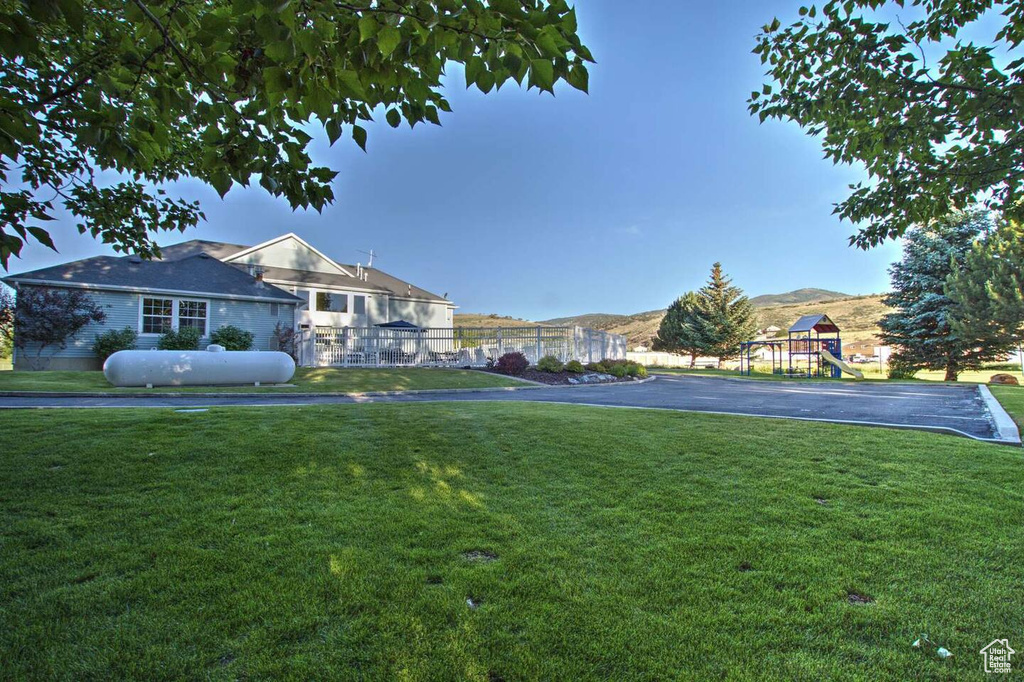 View of property's community featuring a yard, fence, a playground, and a mountain view