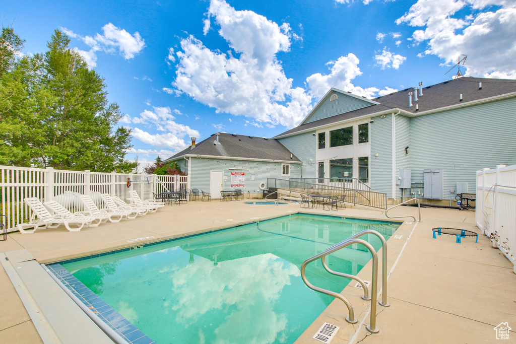 Community pool with a patio area and fence