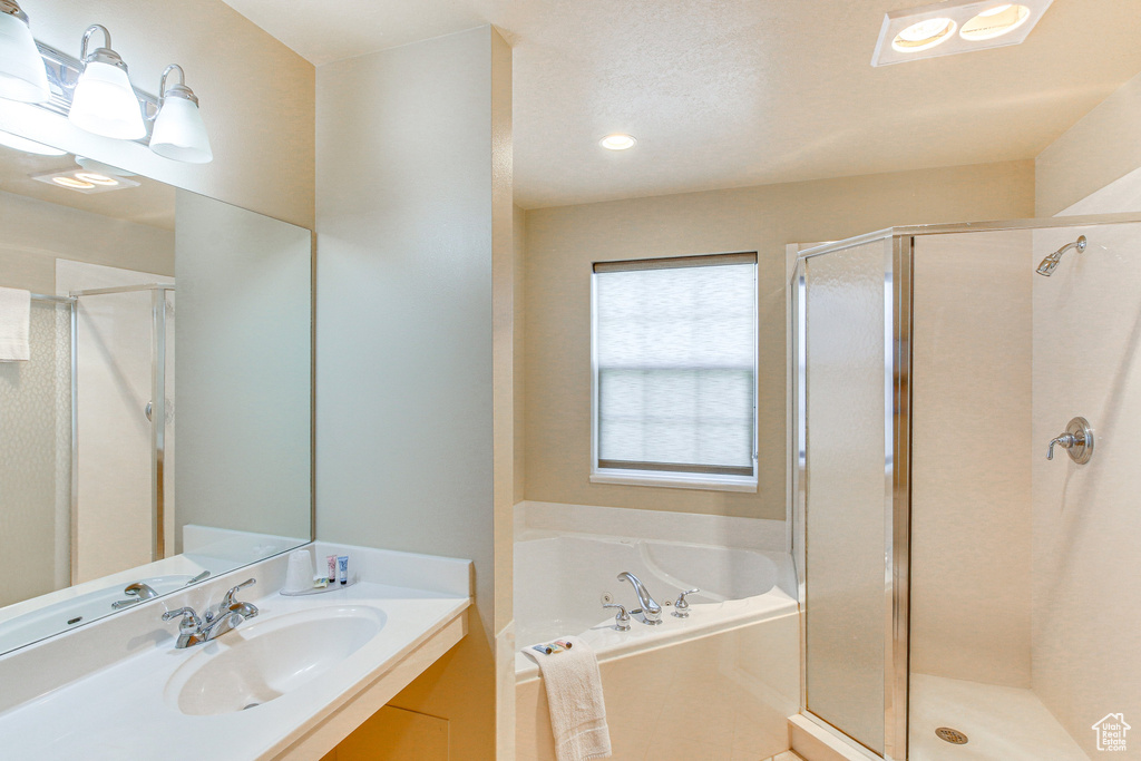 Full bath featuring a stall shower, vanity, and a bath