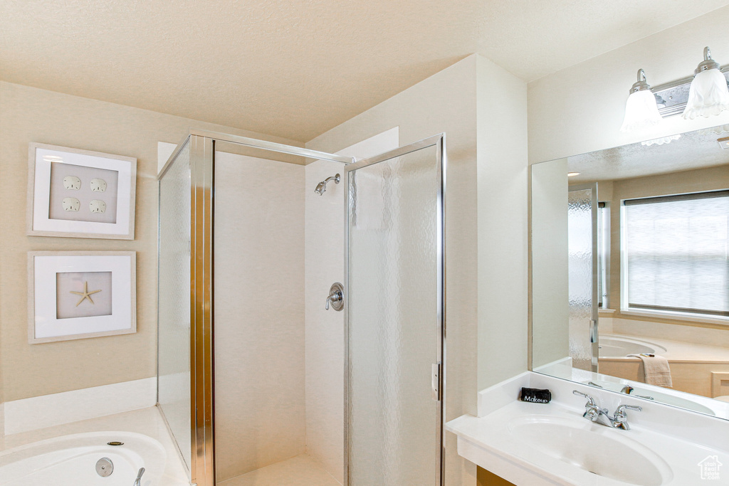 Full bathroom with a bath, a stall shower, and a sink