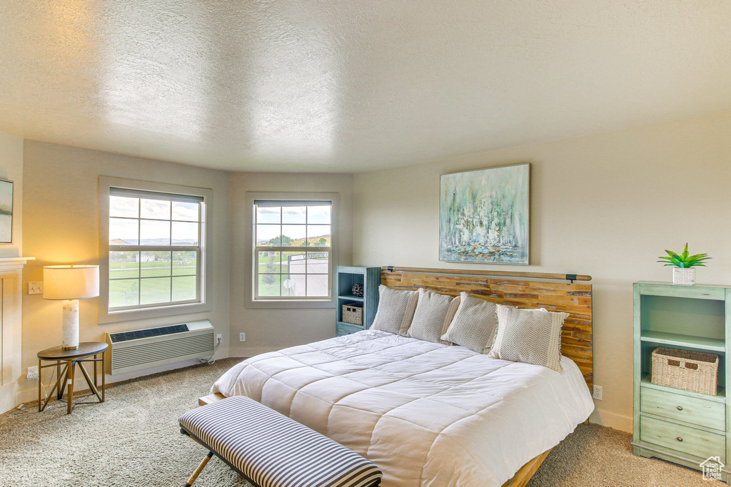 Bedroom featuring carpet flooring, a wall mounted air conditioner, and baseboards