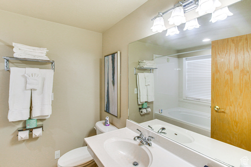 Full bathroom with toilet, shower / bath combination, an inviting chandelier, and a sink