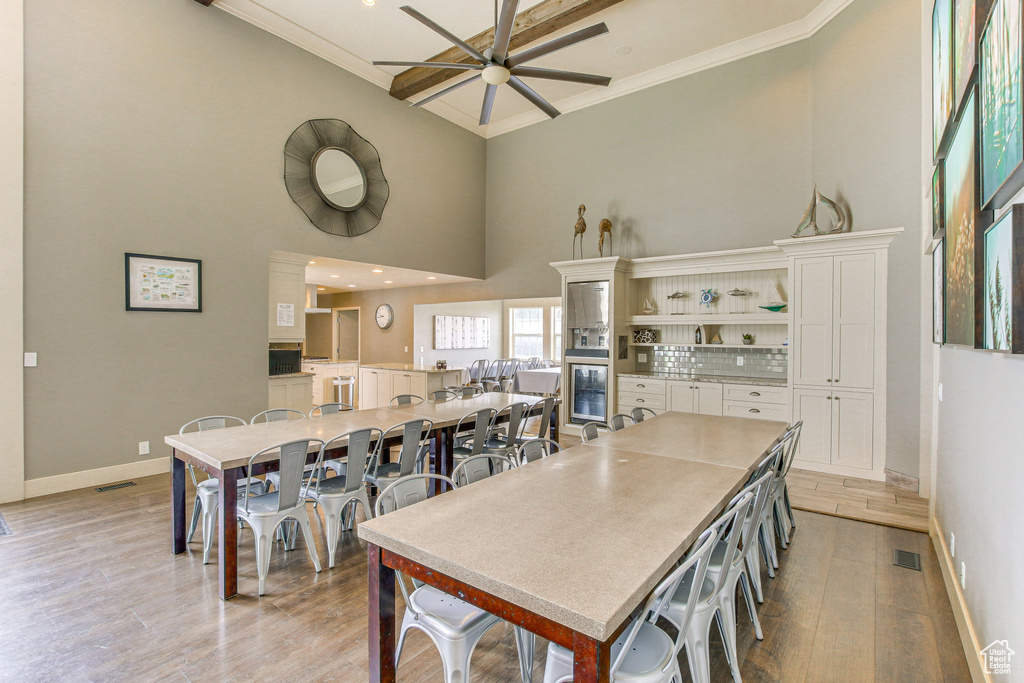 Kitchen featuring a high ceiling, white cabinets, baseboards, ceiling fan, and wine cooler