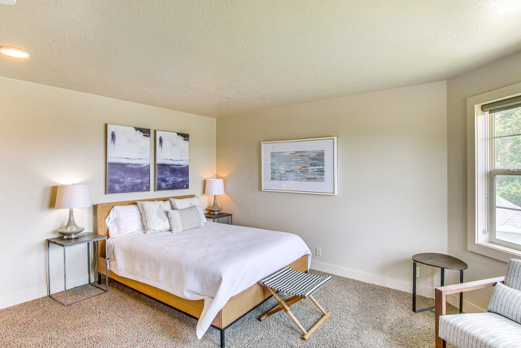 Bedroom with light colored carpet, a textured ceiling, and baseboards