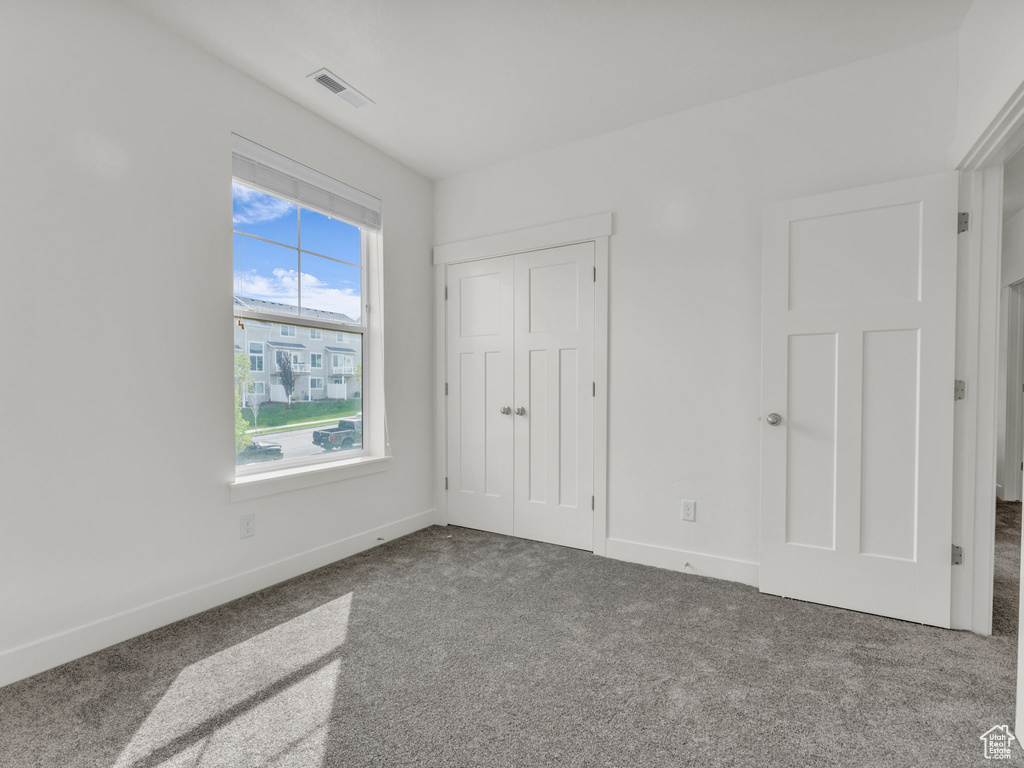 Unfurnished bedroom featuring carpet flooring, baseboards, and a closet
