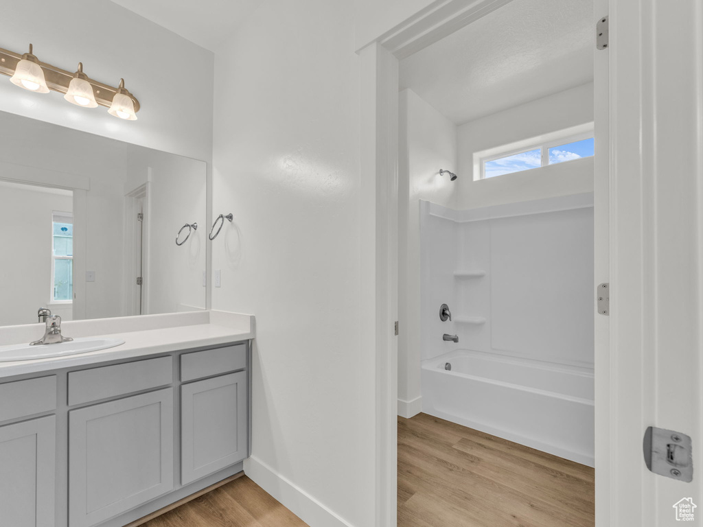 Bathroom with wood finished floors, vanity, washtub / shower combination, and baseboards