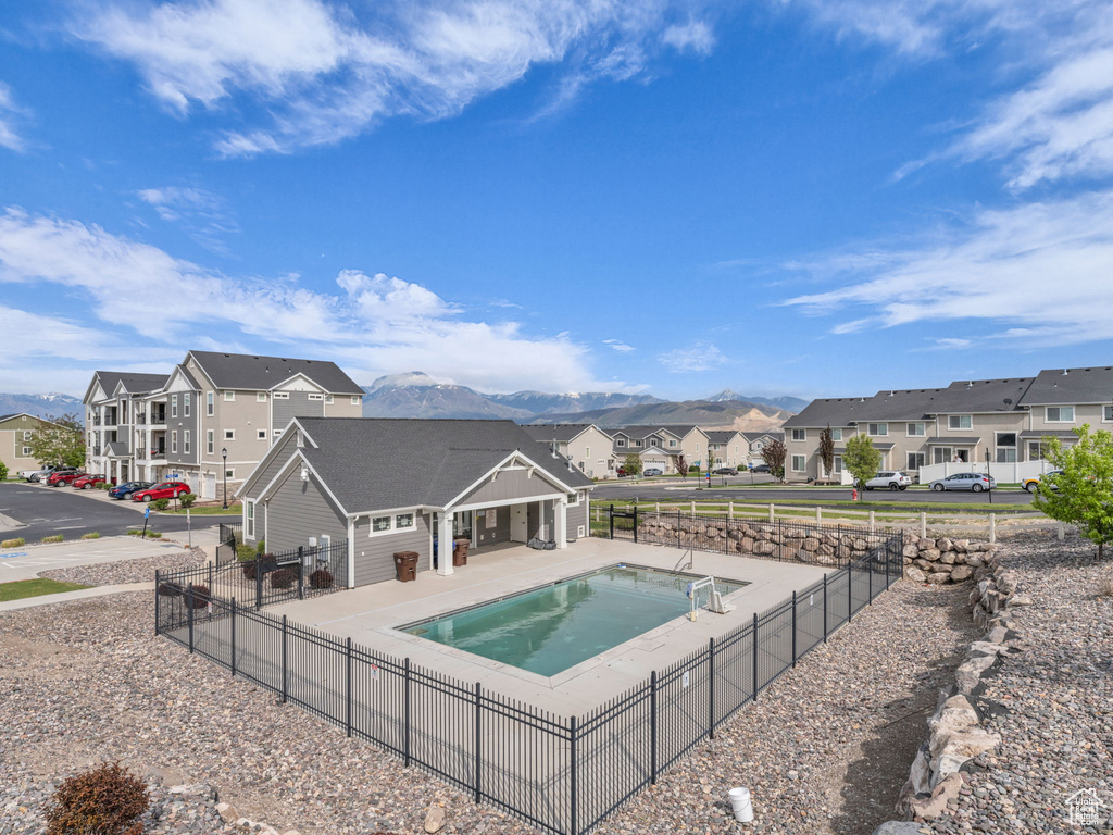 Community pool featuring a residential view, a mountain view, fence, and a patio area