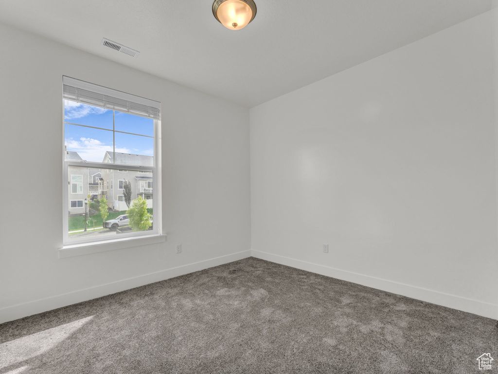 Empty room featuring dark colored carpet and baseboards