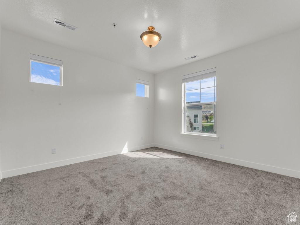 Empty room featuring carpet, baseboards, and fire sprinkler in ceiling