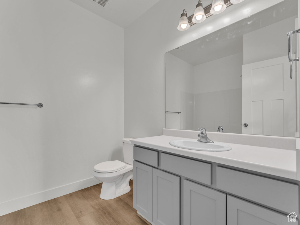 Bathroom with wood finished floors, baseboards, vanity, and toilet