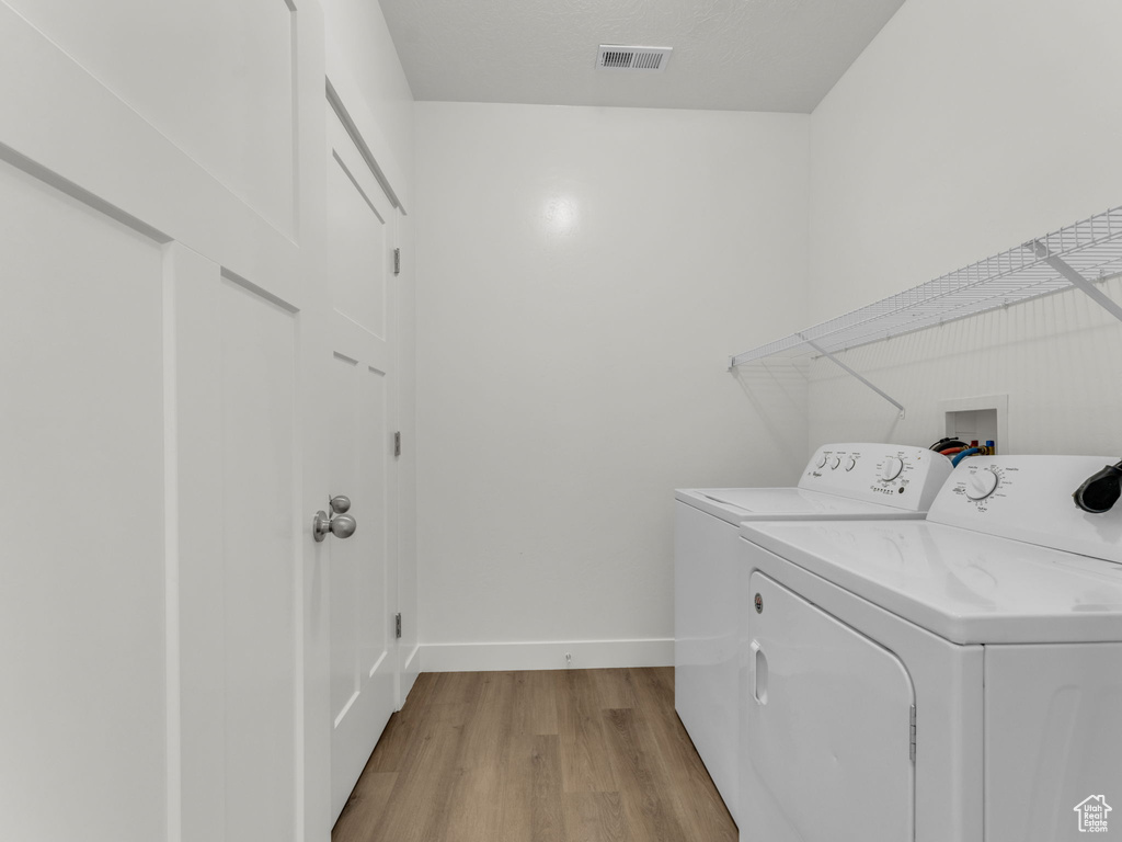 Laundry room featuring washing machine and dryer, light wood-style flooring, and baseboards