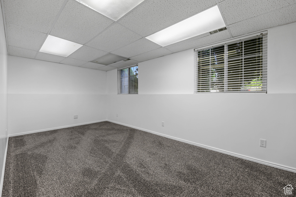 Empty room with a paneled ceiling, carpet, and baseboards