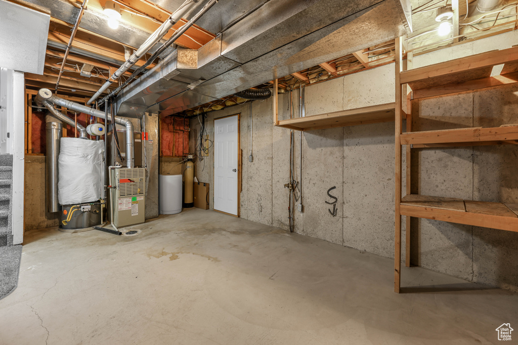 Unfinished below grade area featuring heating unit and a water softener