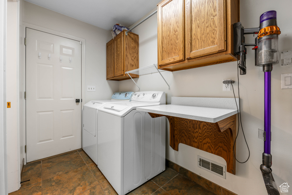 Laundry room featuring washer and dryer, cabinet space, and stone tile flooring