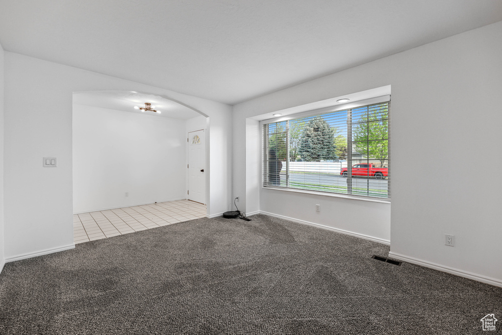 Spare room with carpet, arched walkways, baseboards, and tile patterned flooring