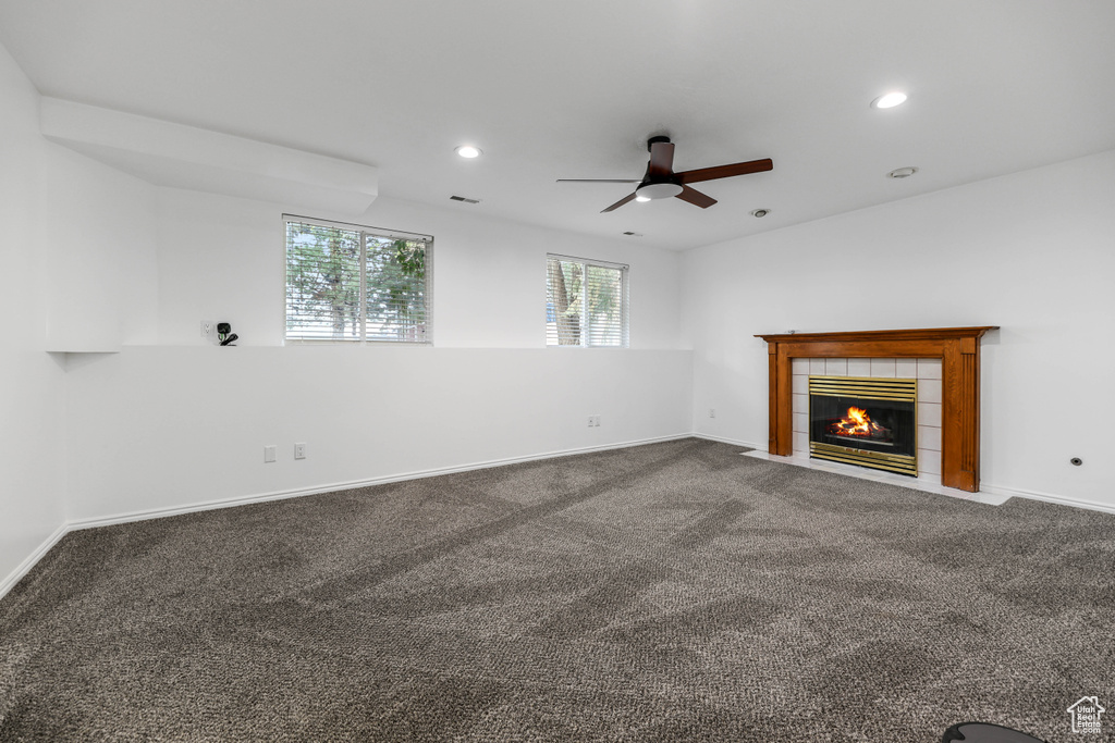 Unfurnished living room featuring a ceiling fan, recessed lighting, carpet floors, a tiled fireplace, and baseboards