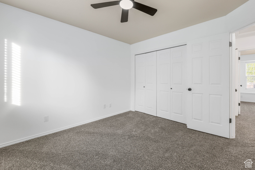 Unfurnished bedroom with carpet, a closet, baseboards, and ceiling fan