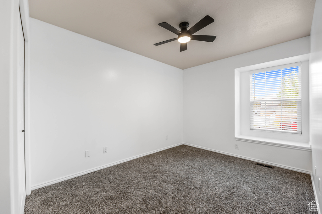 Carpeted spare room with a ceiling fan and baseboards