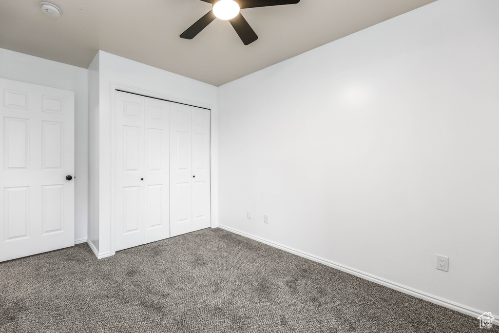 Unfurnished bedroom featuring carpet, baseboards, a closet, and ceiling fan
