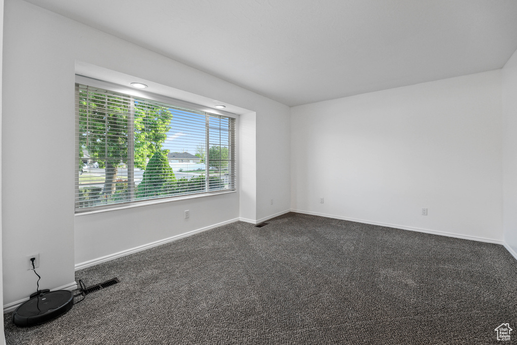 Unfurnished room featuring baseboards and dark colored carpet