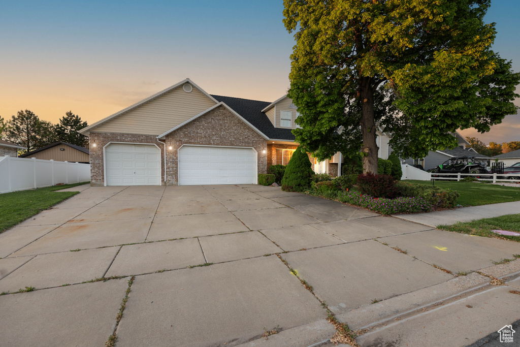 View of front facade featuring a garage, driveway, and brick siding