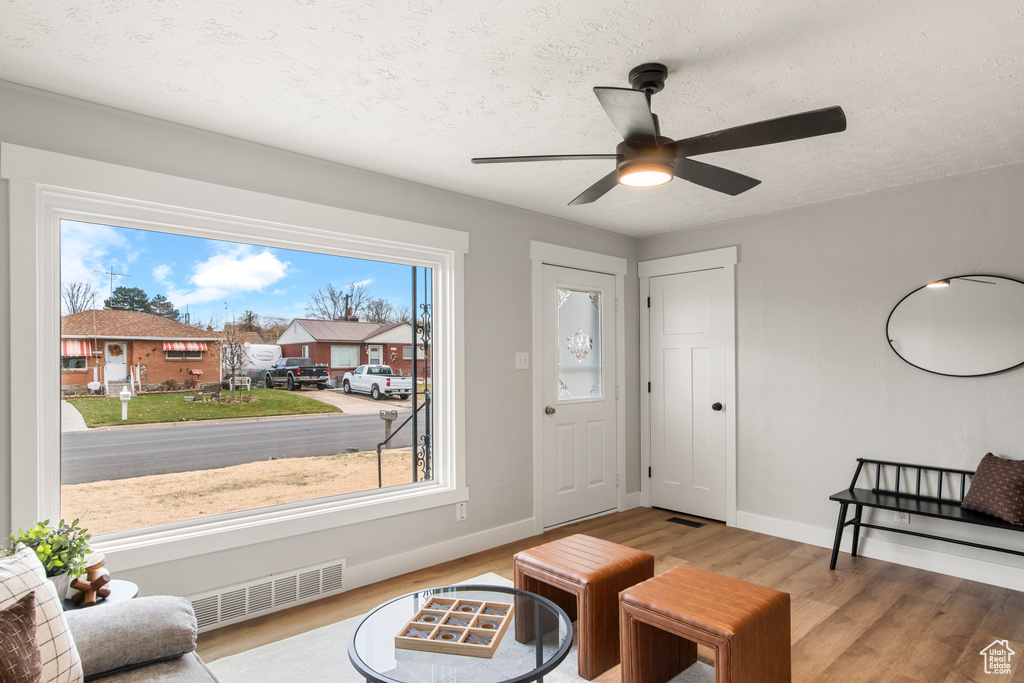 Living area featuring wood finished floors, baseboards, ceiling fan, and a textured ceiling
