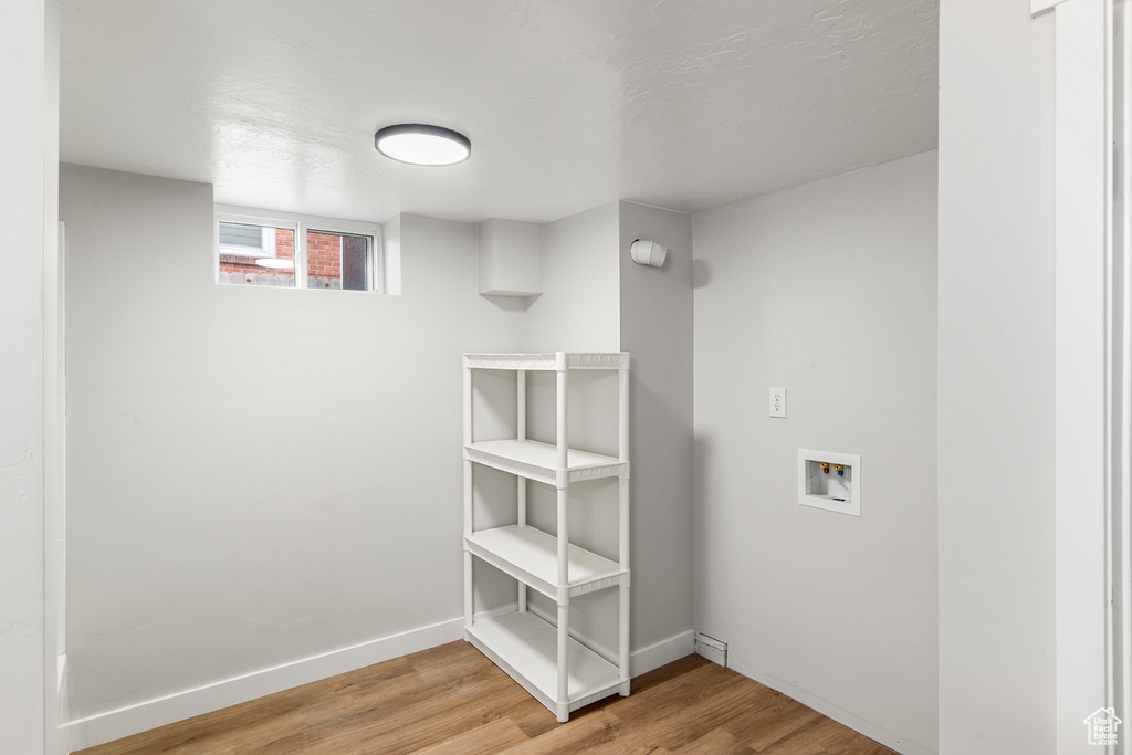 Laundry room featuring washer hookup, light wood-style floors, and baseboards