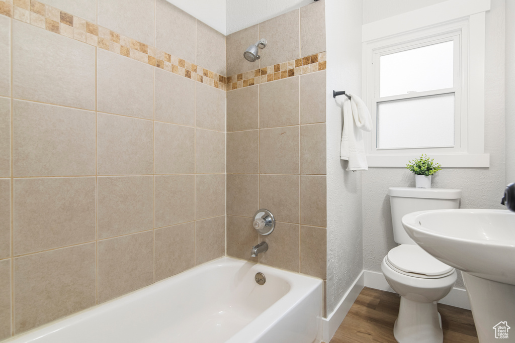 Bathroom featuring toilet, wood finished floors, shower / tub combination, and baseboards