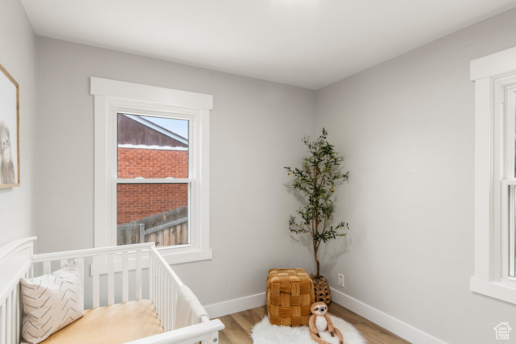 Bedroom with light wood finished floors, baseboards, and a nursery area