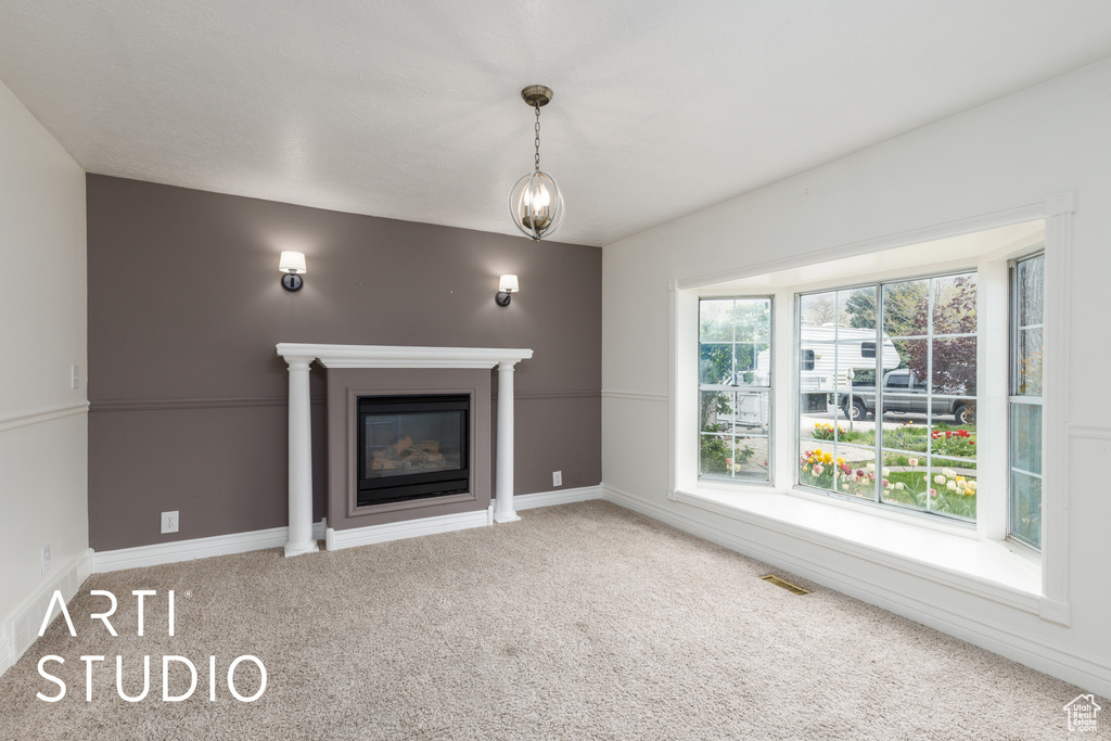 Unfurnished living room with carpet, visible vents, baseboards, and a glass covered fireplace