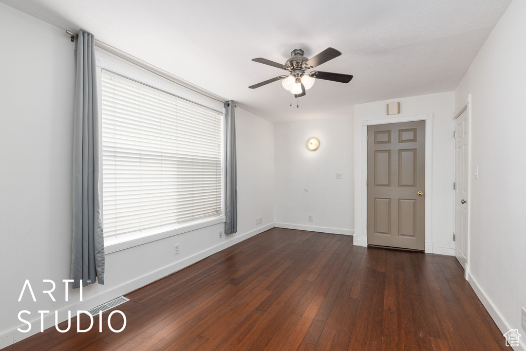 Unfurnished room featuring dark wood-type flooring, baseboards, visible vents, and ceiling fan