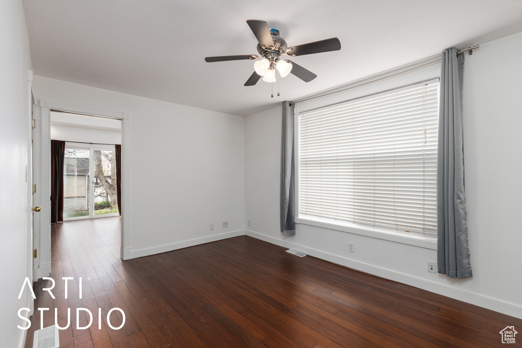 Unfurnished room with visible vents, baseboards, ceiling fan, and dark wood-type flooring