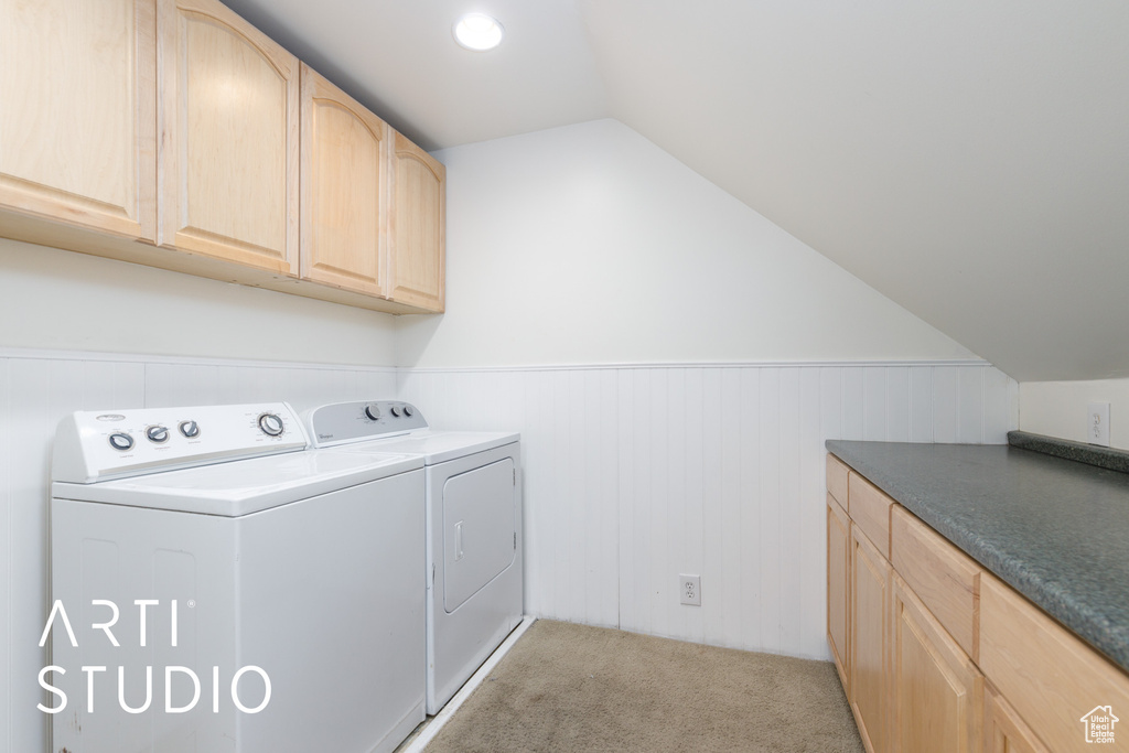 Washroom featuring wainscoting, separate washer and dryer, light colored carpet, and cabinet space