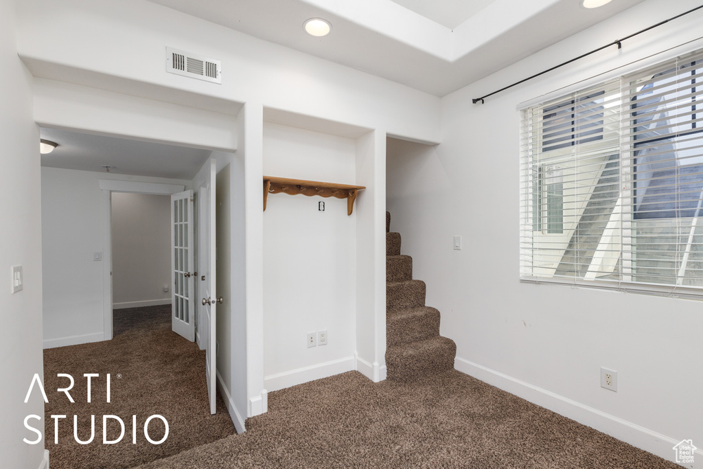 Interior space featuring stairway, carpet floors, baseboards, and visible vents