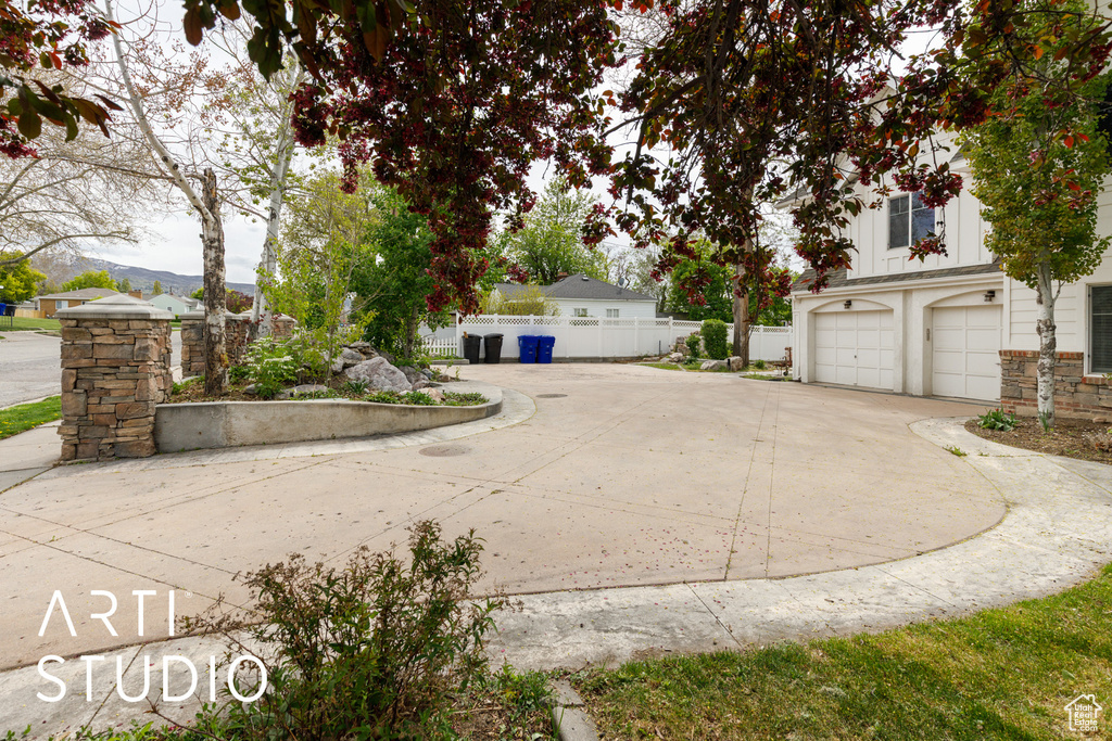 Exterior space with stone siding, a mountain view, driveway, and fence