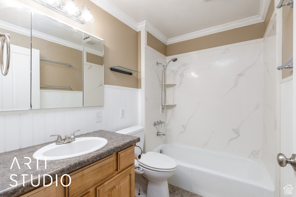 Full bathroom featuring toilet, ornamental molding, vanity, bathtub / shower combination, and a wainscoted wall