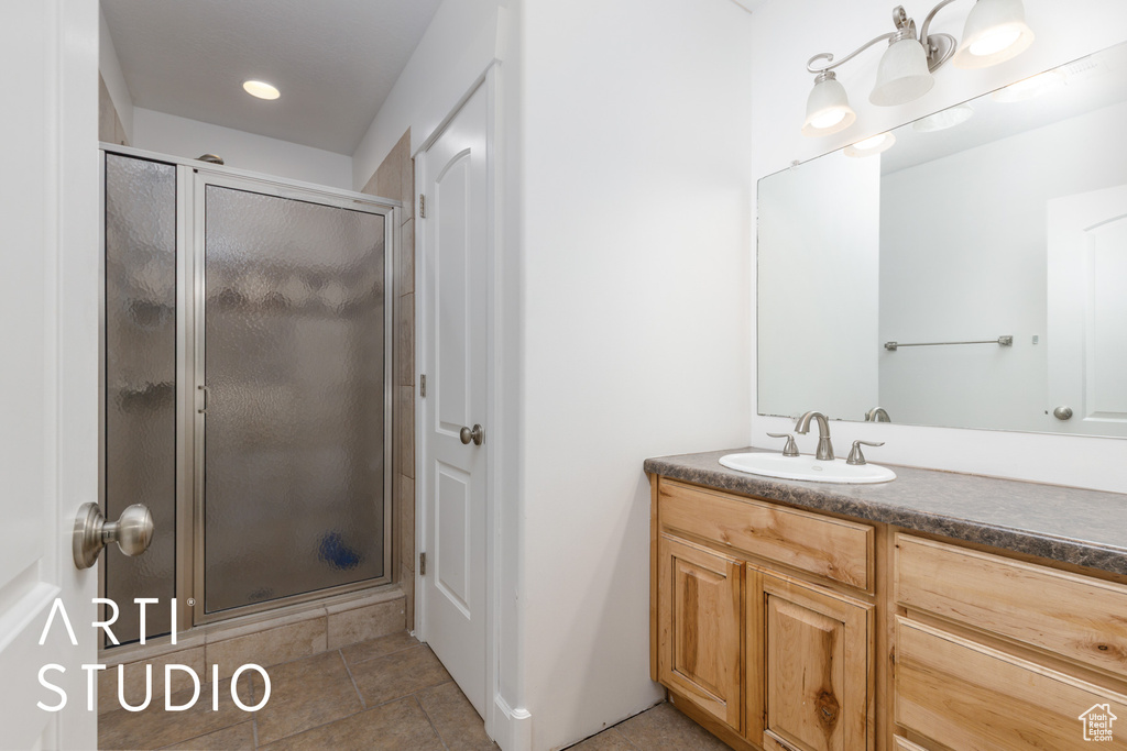 Full bath featuring vanity, tile patterned flooring, and a shower stall