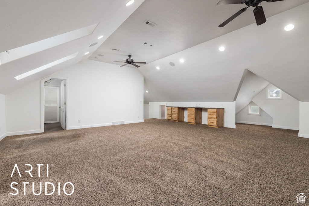 Additional living space with lofted ceiling with skylight, visible vents, ceiling fan, and carpet